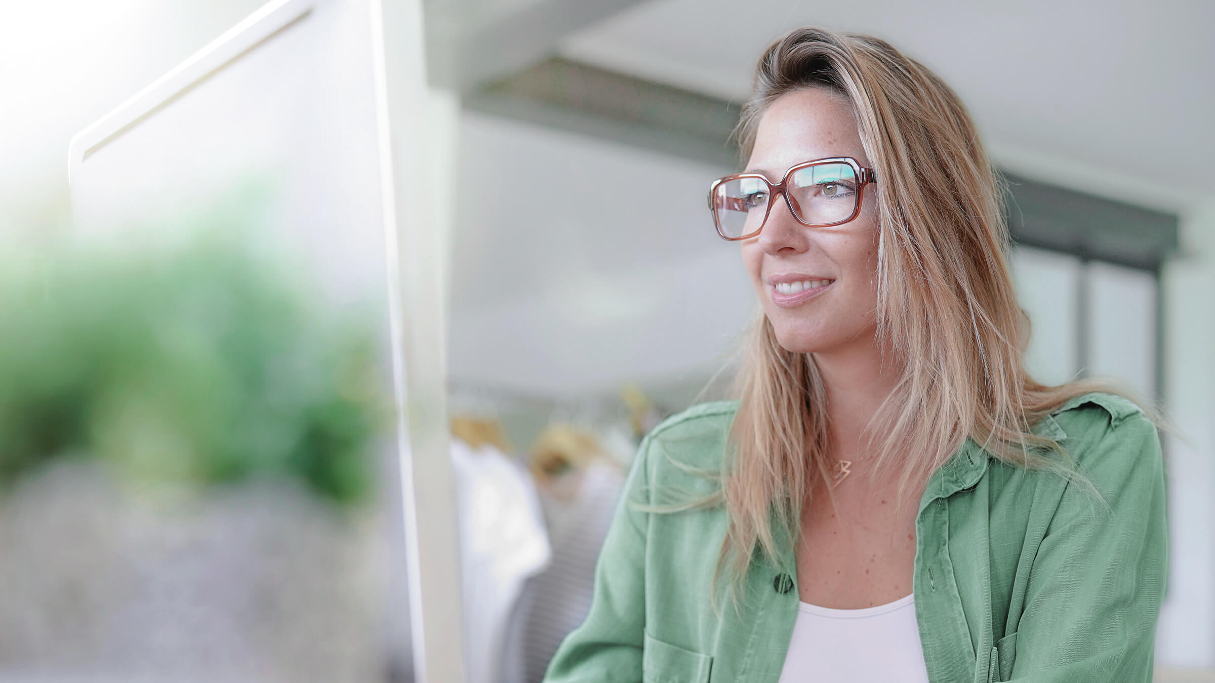 Spokojená klientka LYNX v zelené košili s brýlemi, která investuje do certifikátů